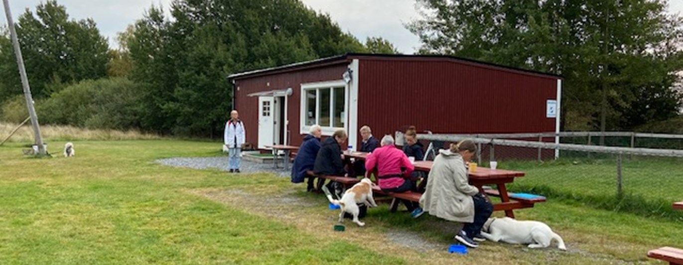 Hundägare som fikar utanför klubbstugan.
