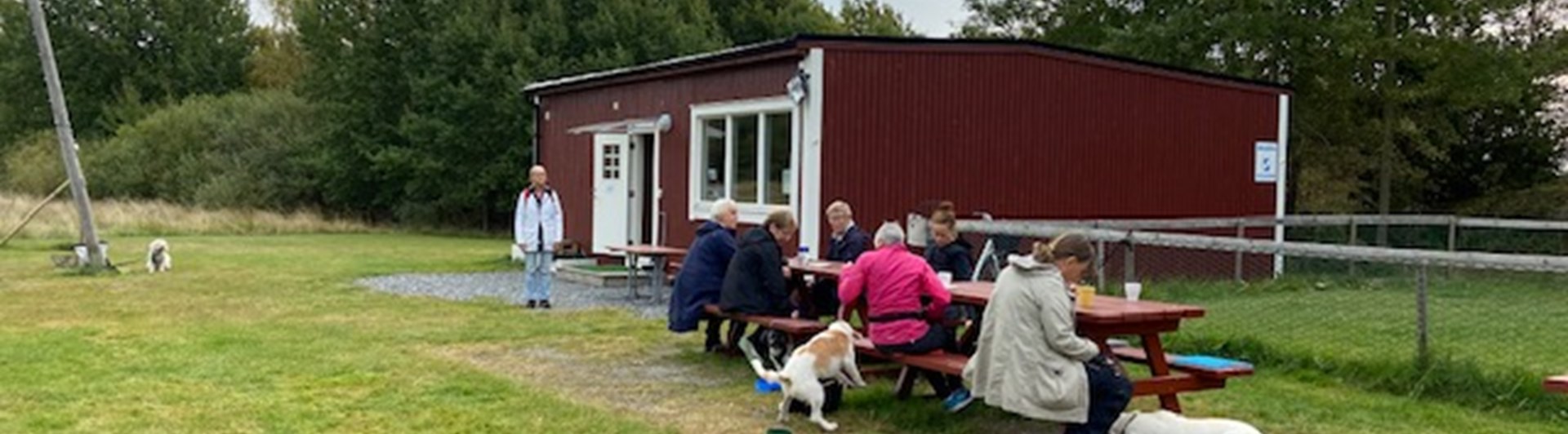 Hundägare som fikar utanför klubbstugan.