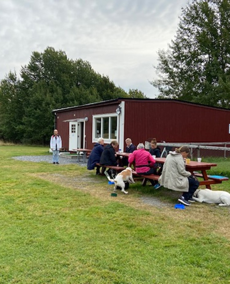 Hundägare som fikar utanför klubbstugan.