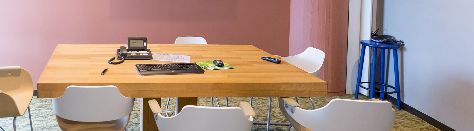 Bild på mindre konferensrum med bord och stolar.