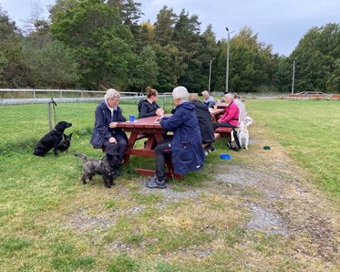 Hundägare som fikar utanför klubbstugan.