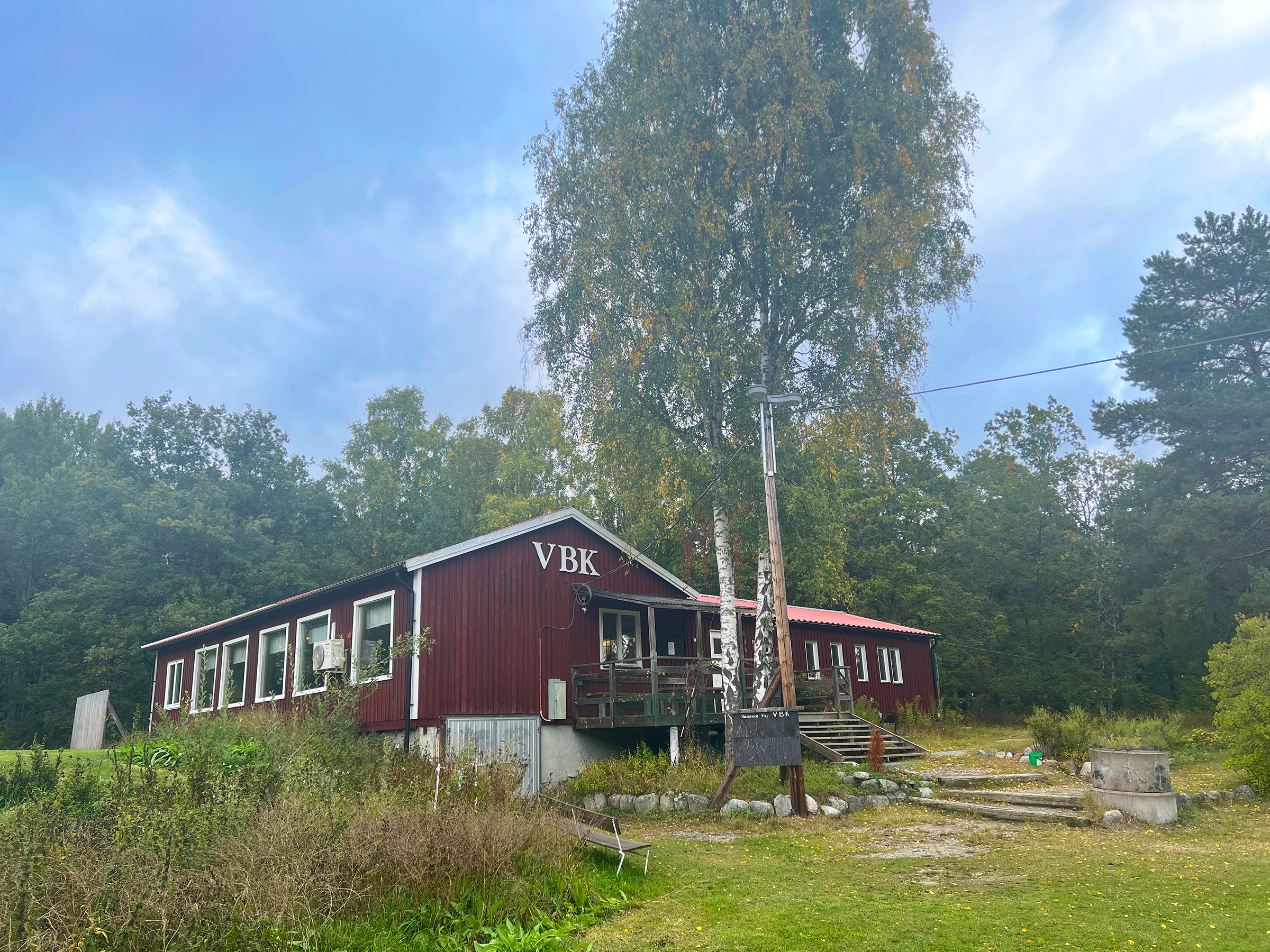 Röd klubbstuga i trä med texten VBK.