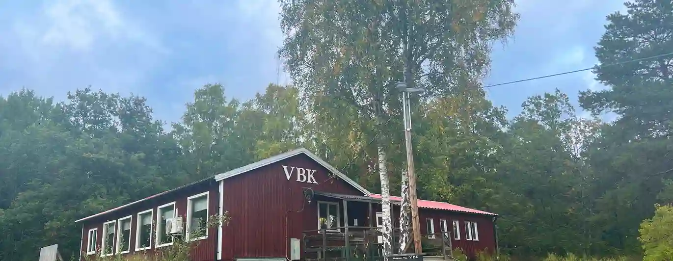 Röd klubbstuga i trä med texten VBK.