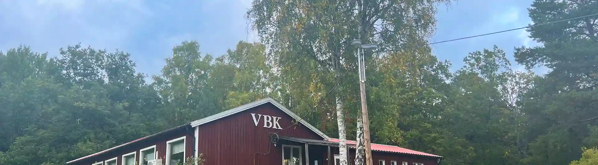 Röd klubbstuga i trä med texten VBK.