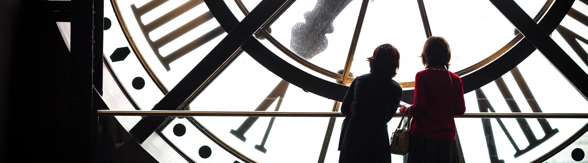 Bild som visar två kvinnosiluetter som står inuti en stor klocka.