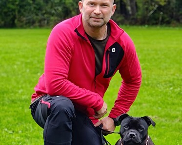 Staffordshire bullterrier sitter bredvid sin husse