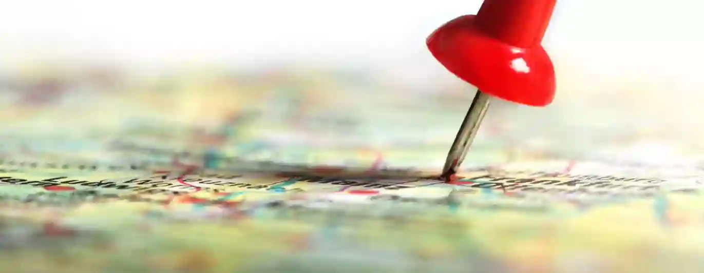 Bild med en röd nål på en karta i färg.