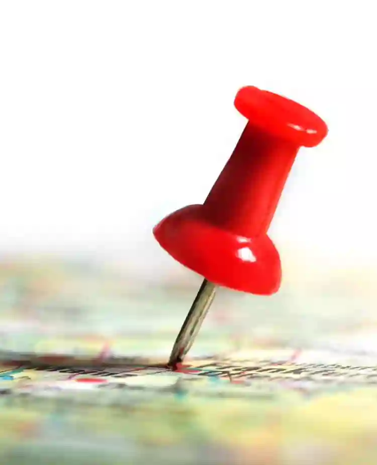 Bild med en röd nål på en karta i färg.