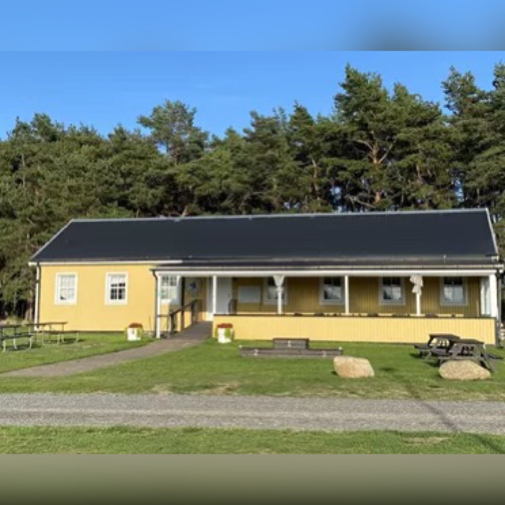 Ett avlångt gult hus med en altan på framsidan 