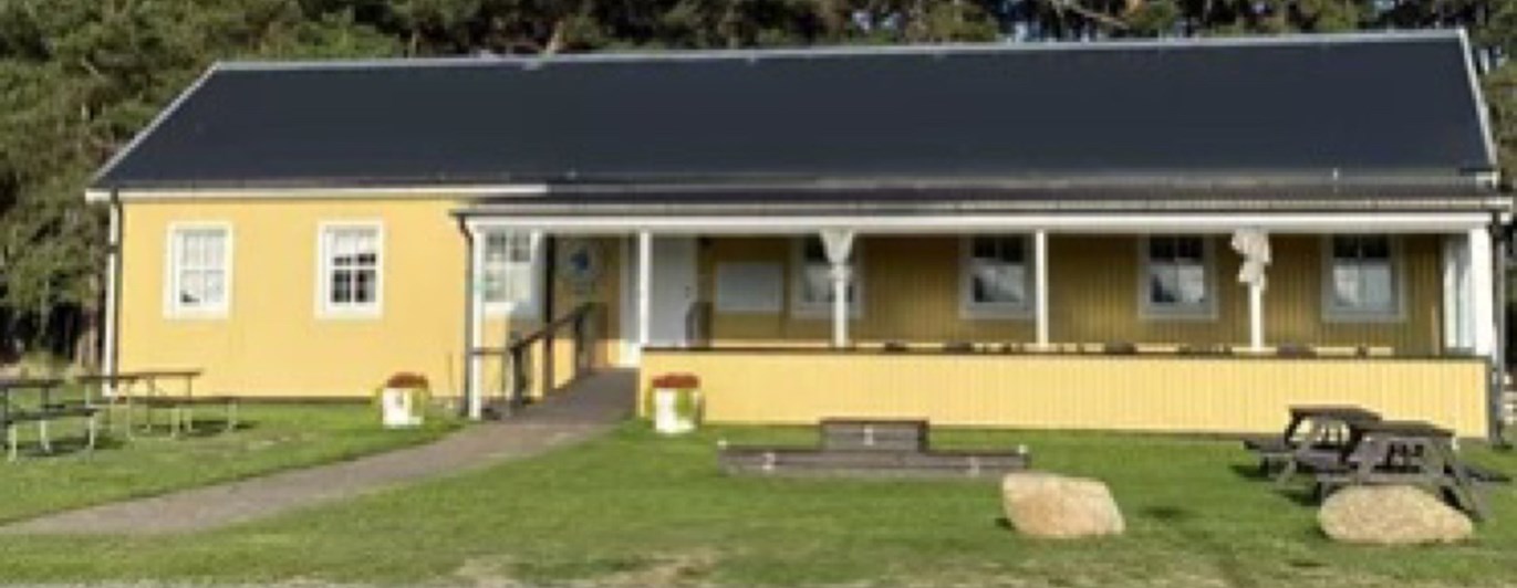 Ett avlångt gult hus med en altan på framsidan