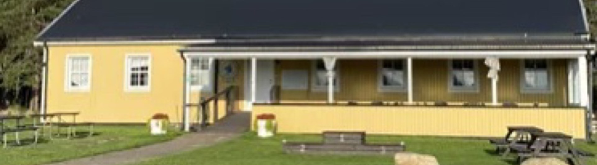 Ett avlångt gult hus med en altan på framsidan