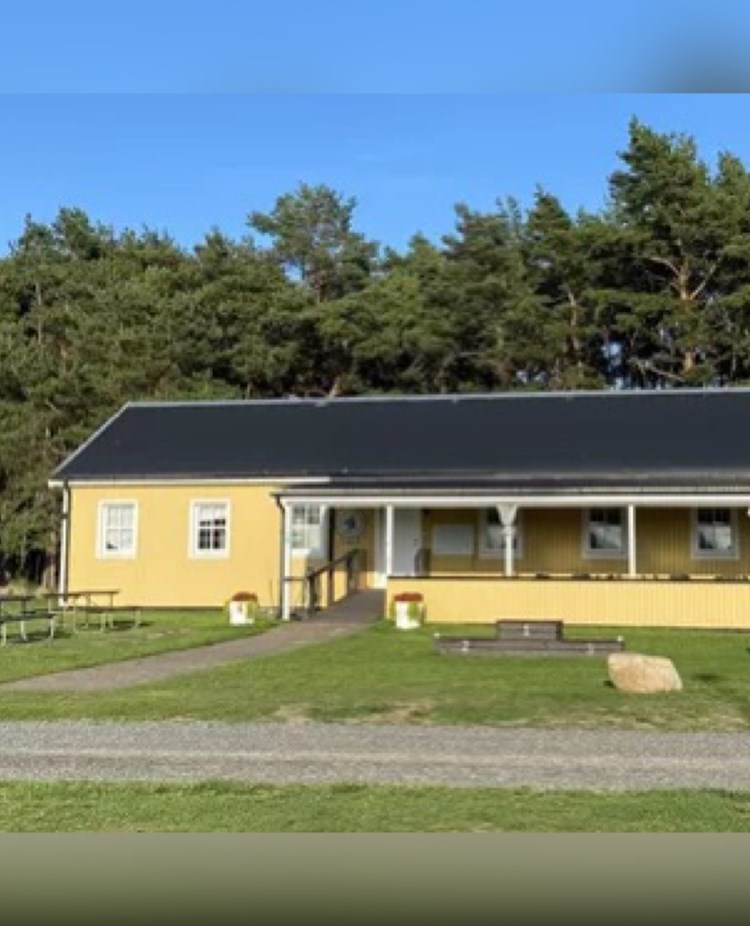 Ett avlångt gult hus med en altan på framsidan