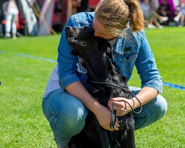 En bild på ett ekipage där föraren kramar om sin svarta hund
