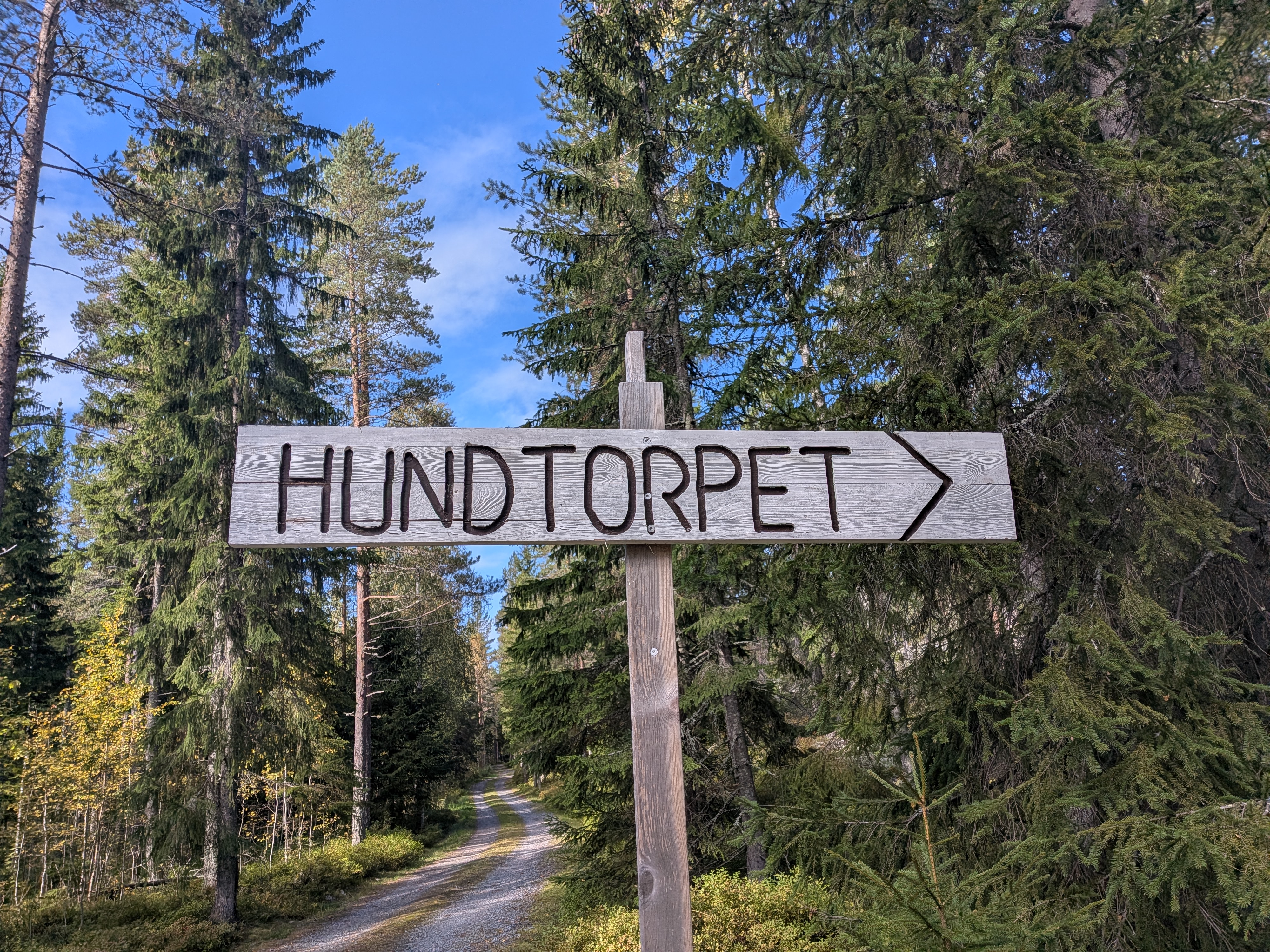 Skylt i trä med texten Hundtorpet och en pil.
