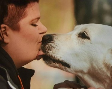 Kvinna pussar på sin vita hund.