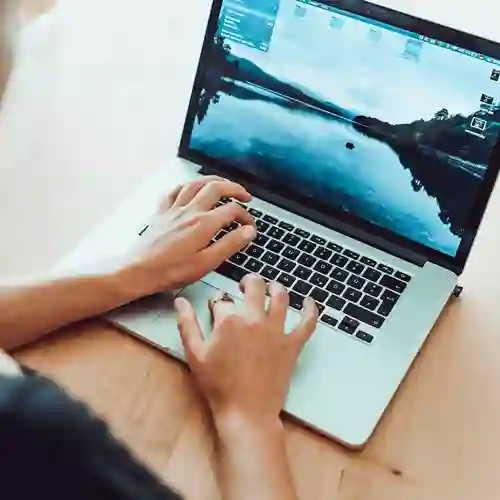 Person som sitter och skriver på dator. 