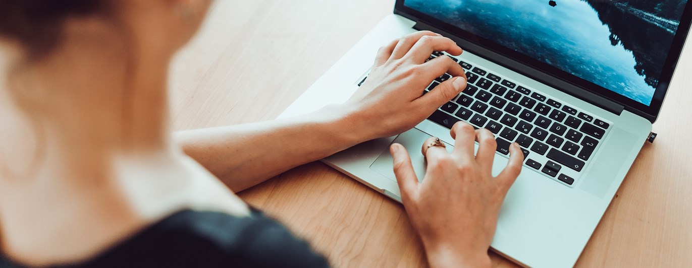 Person som sitter och skriver på dator.