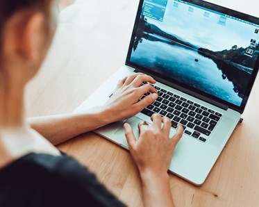 Person som sitter och skriver på dator.