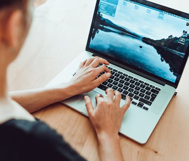 Person som sitter och skriver på dator.