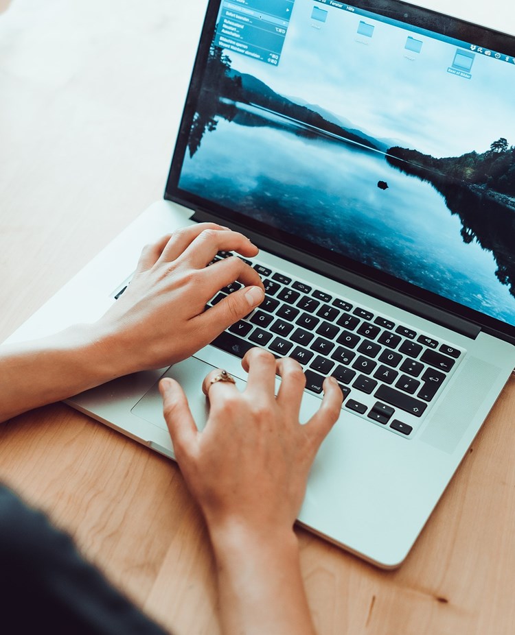 Person som sitter och skriver på dator.