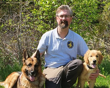 Sommarbild en människa omgiven av två hundar