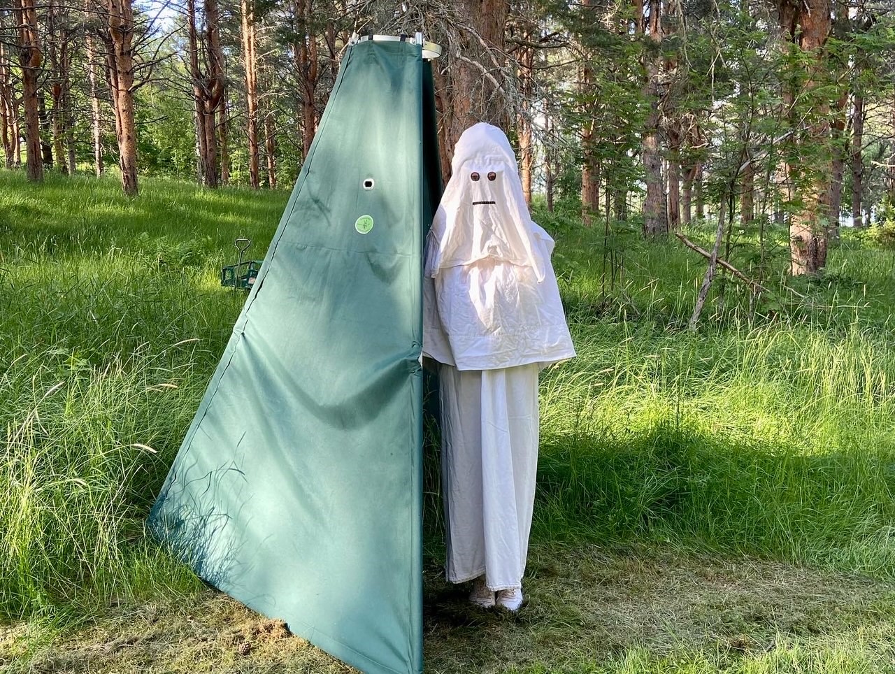 En figurant som är utklädd till ett spöke står vid sitt gröna tält. 