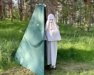 En figurant som är utklädd till ett spöke står vid sitt gröna tält. 
