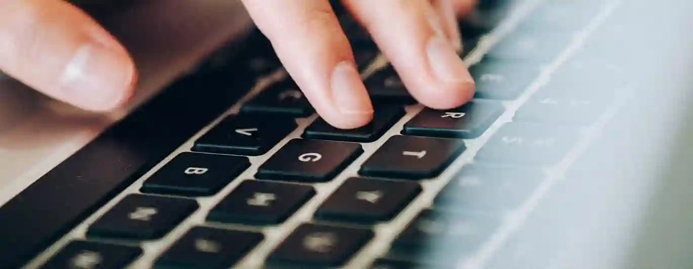 Bild som visar en hand på en bärbar dator.