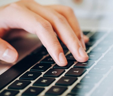 Bild som visar en hand på en bärbar dator.