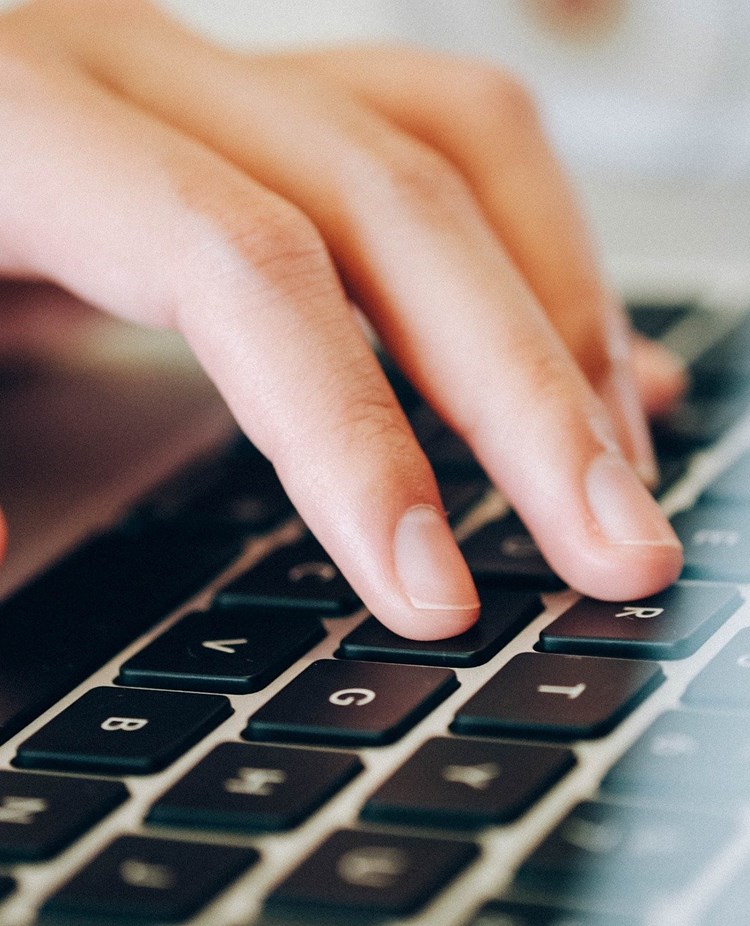 Bild som visar en hand på en bärbar dator.