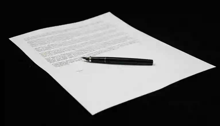 Dokument som ligger på ett svart underlag tillsammans med en penna