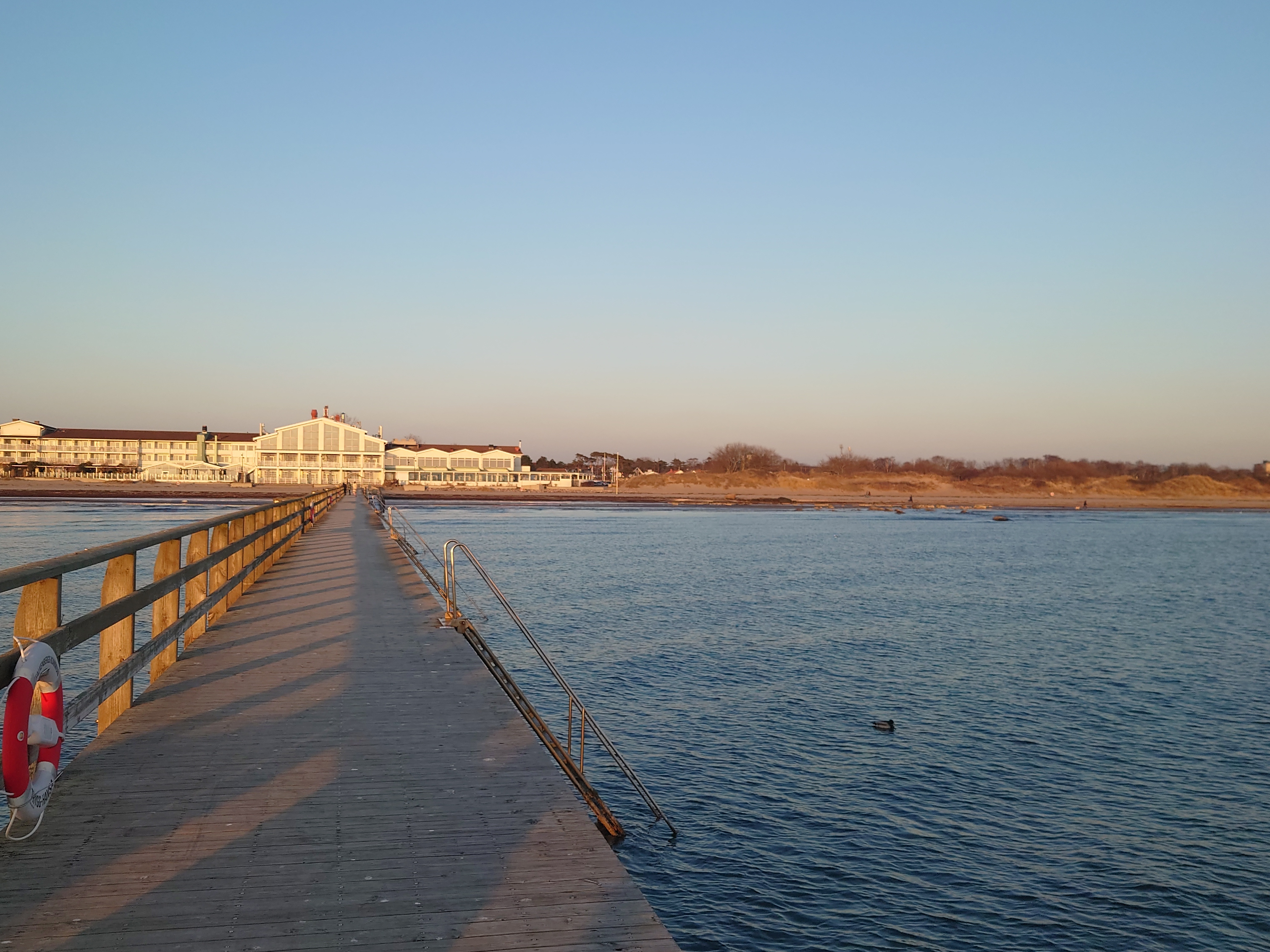 Brygga ut i havet med hotell i bakgrunden