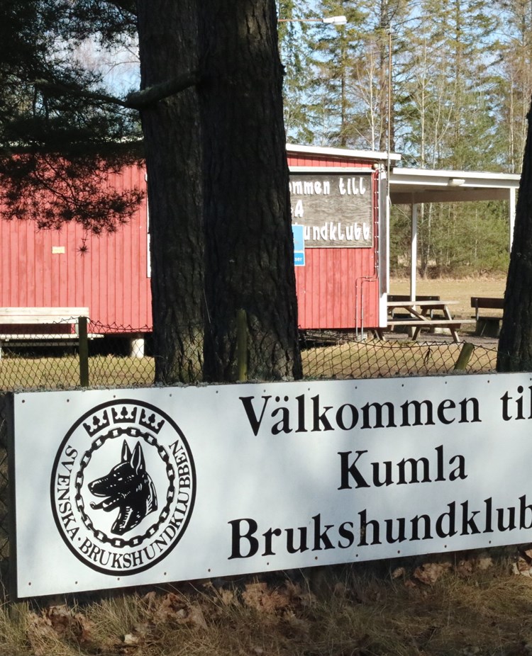 En skylt på Kumla brukshundklubbs klubbstuga och appellplan en solig dag