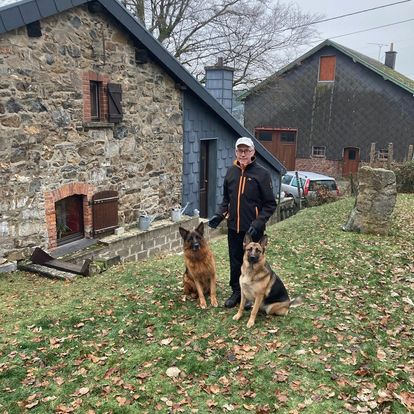 Man som står bakom sina hundar som sitter ner framför honom