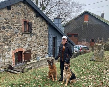 Man som står bakom sina hundar som sitter ner framför honom